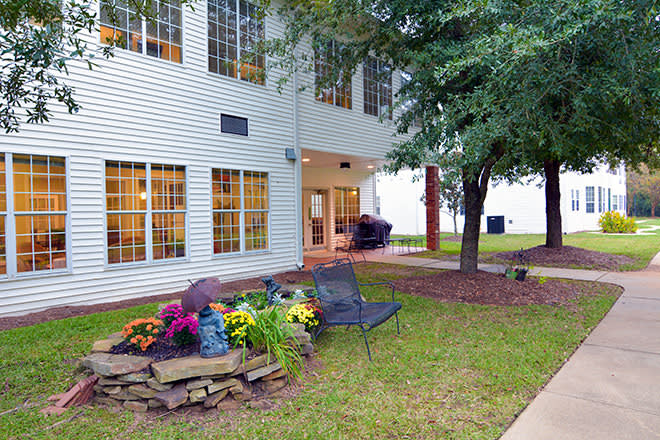 A scenic view of a building exterior with a landscaped garden and seating area.