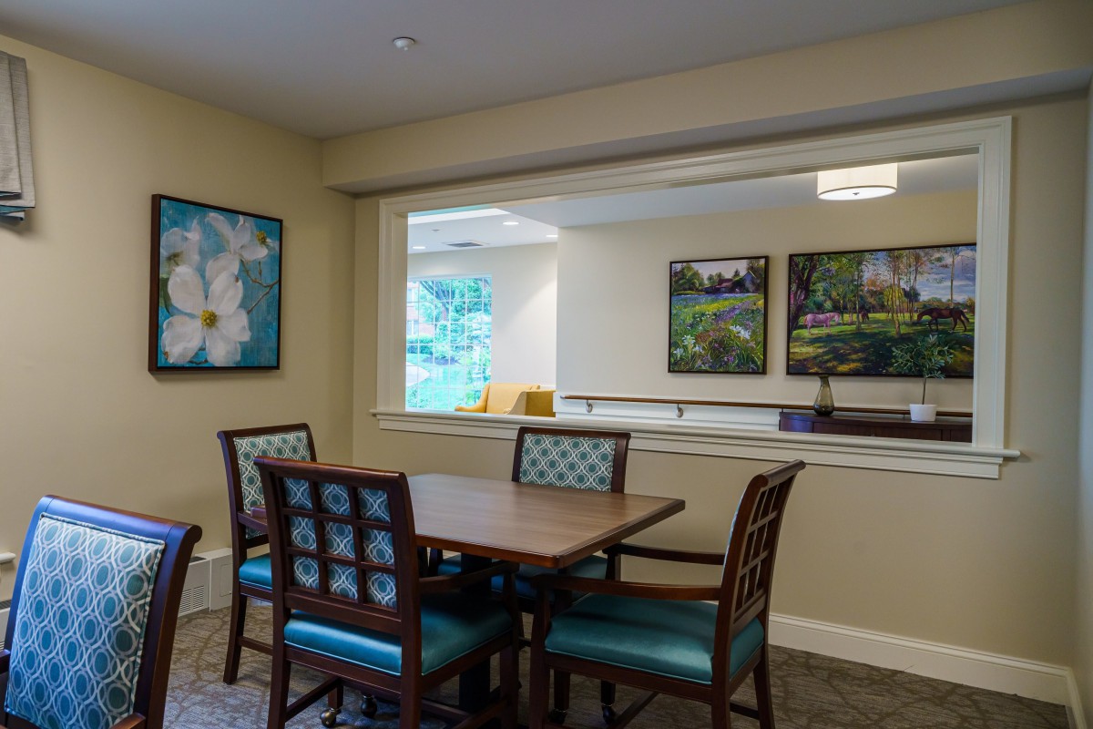 A cozy dining area with a table, chairs, and artwork on the walls.