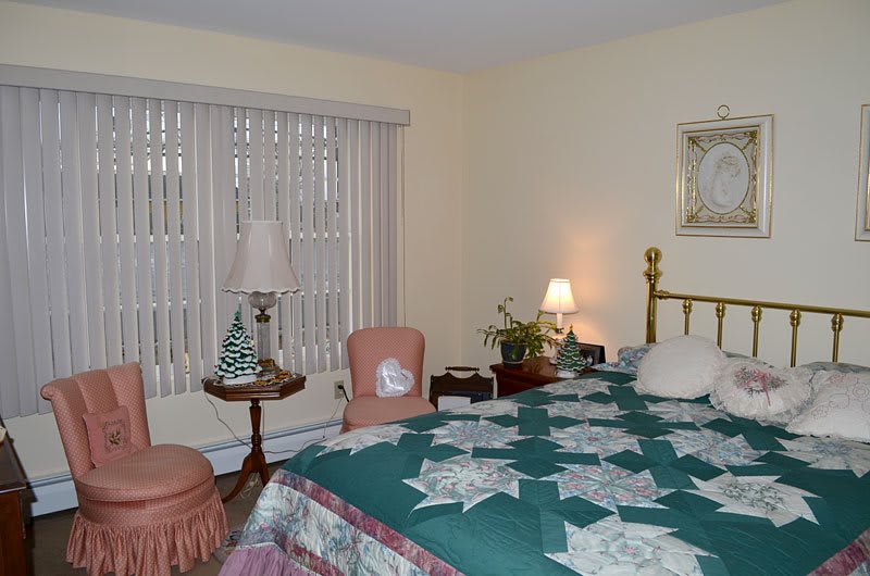A cozy bedroom with a quilt-covered bed, adorned with warm lighting and vintage decor.