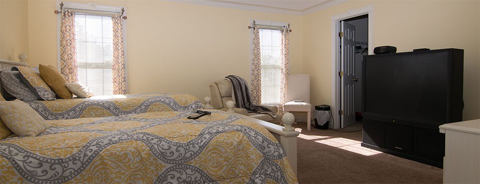 A cozy bedroom with a patterned bedspread and ample natural light.