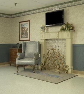 A cozy living room with an armchair, television, and fireplace.