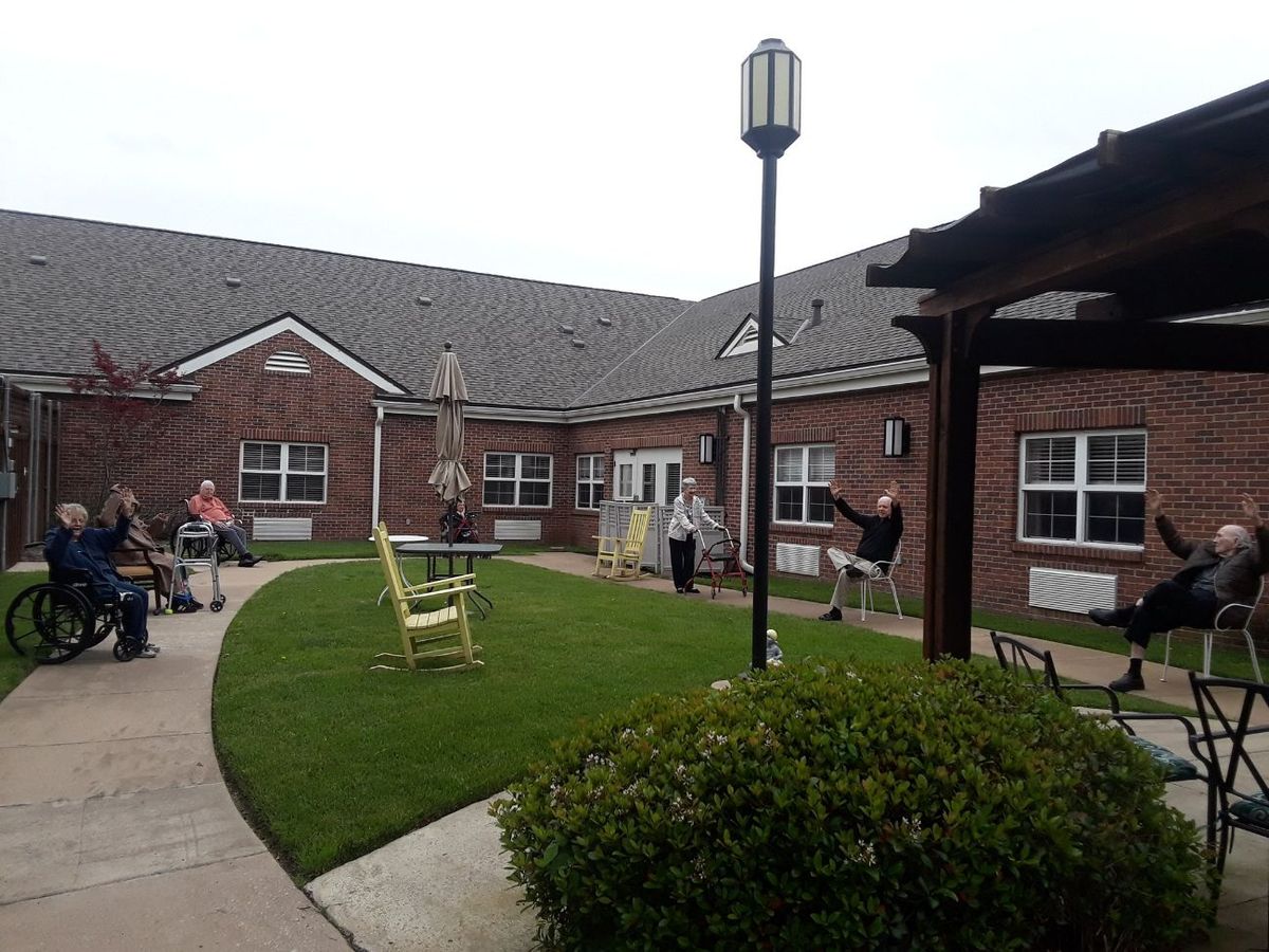 A courtyard with a lawn and pathway surrounded by a brick building, with people enjoying the outdoor space.