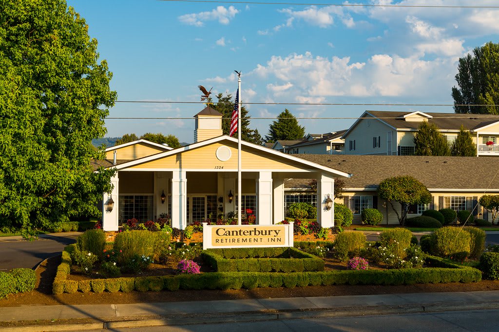 A retirement community with well-maintained gardens and an American flag at the entrance.