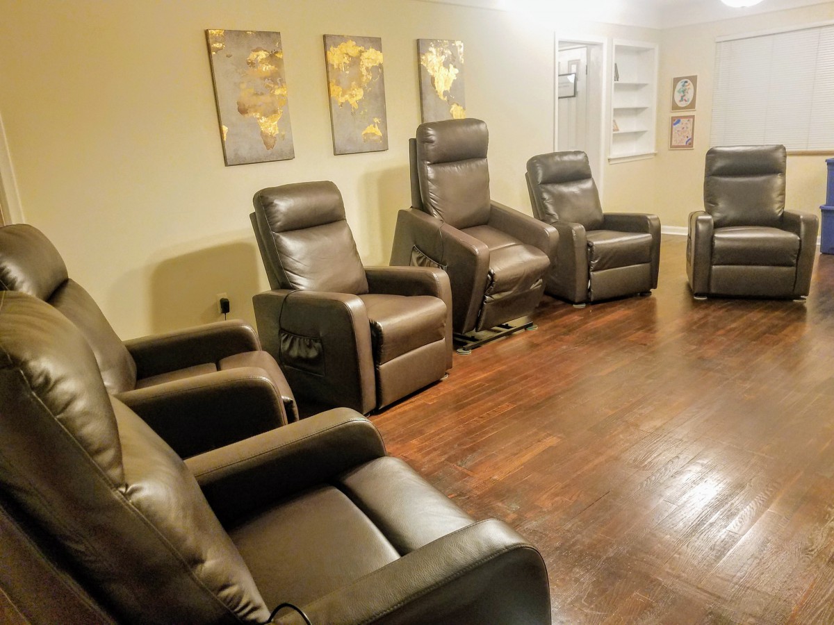 A cozy home theater setup with leather recliner chairs arranged in a room with wooden flooring.