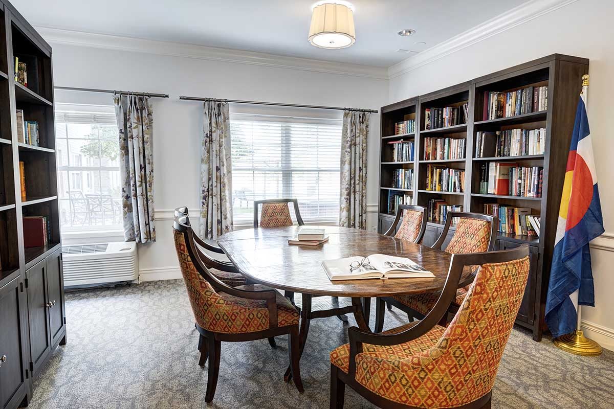 A cozy reading room with a round table and chairs surrounded by bookshelves.