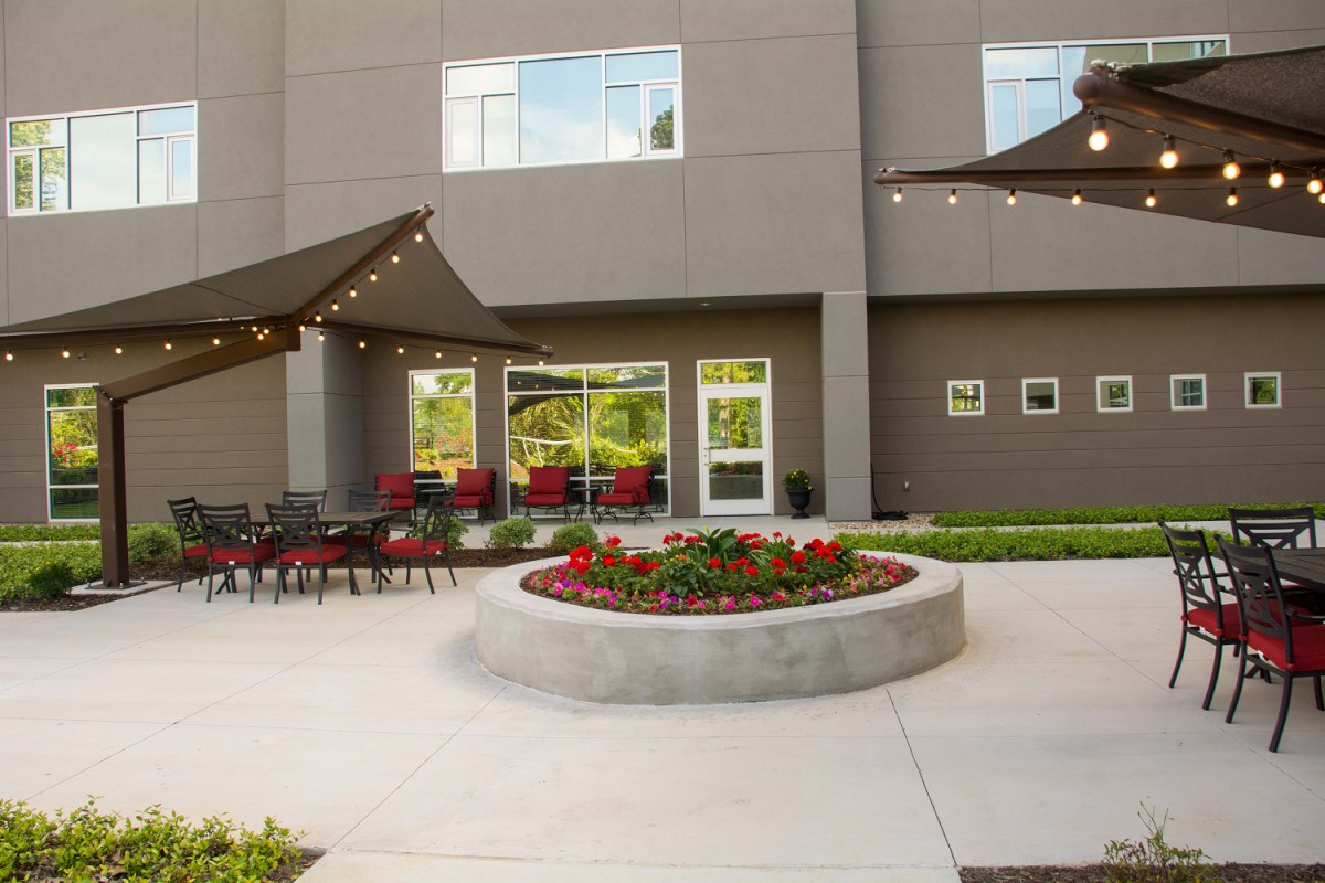 Outdoor patio area with seating and string lights next to a building.