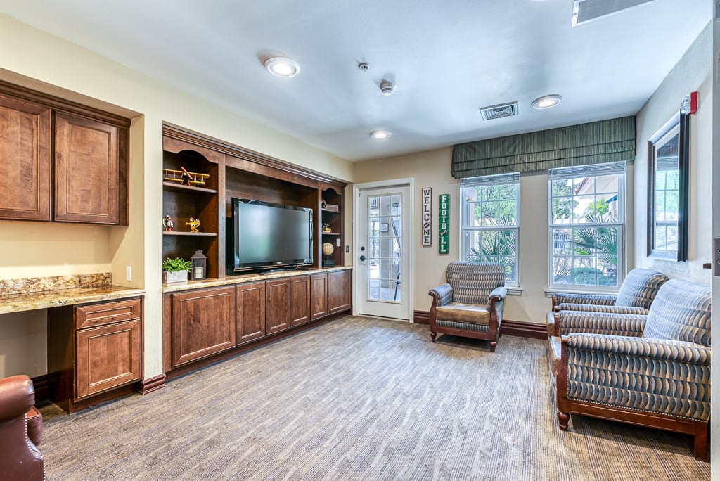 A cozy living room with a television, bookshelves, and comfortable seating.