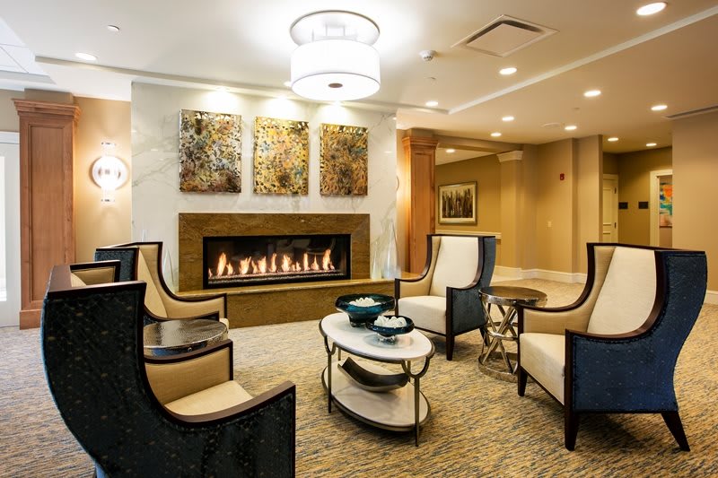 A modern living room with elegant seating, a central fireplace, and decorative art on the walls.