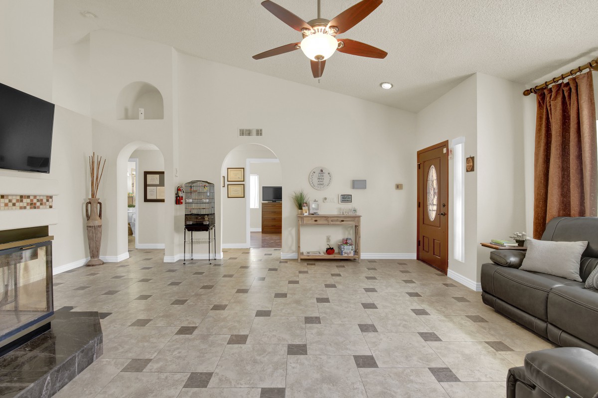 A spacious living room with tile flooring, a ceiling fan, and decorative elements.