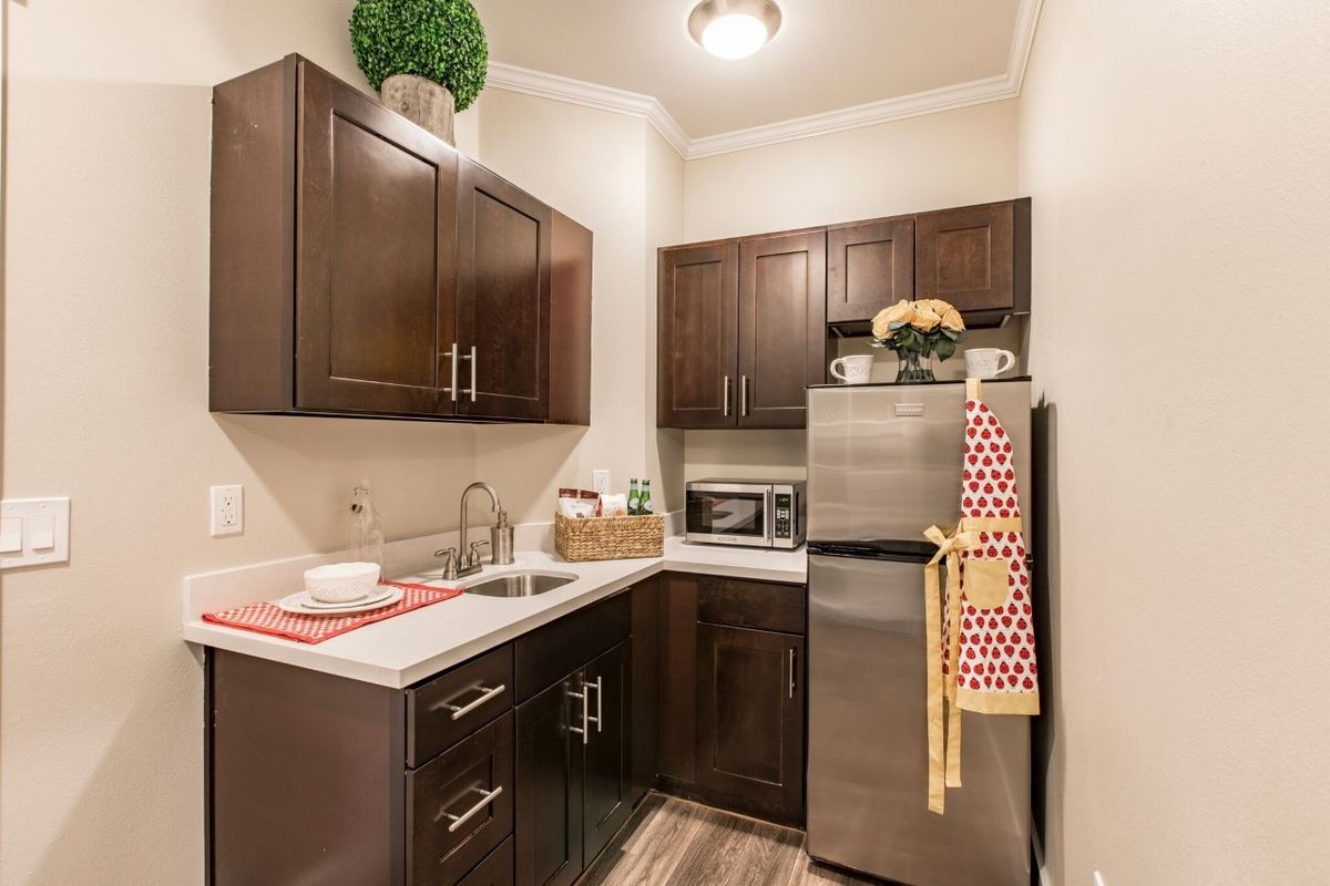 A modern kitchen with wood cabinets and stainless steel appliances in a small, well-organized space.