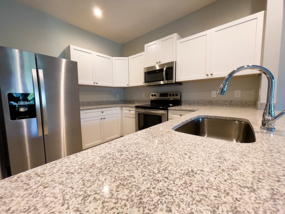 A modern kitchen featuring white cabinets and granite countertops with stainless steel appliances.