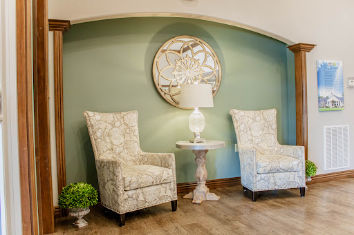 A cozy and inviting corner of a living room featuring stylish chairs, a lamp, and decorative wall art.