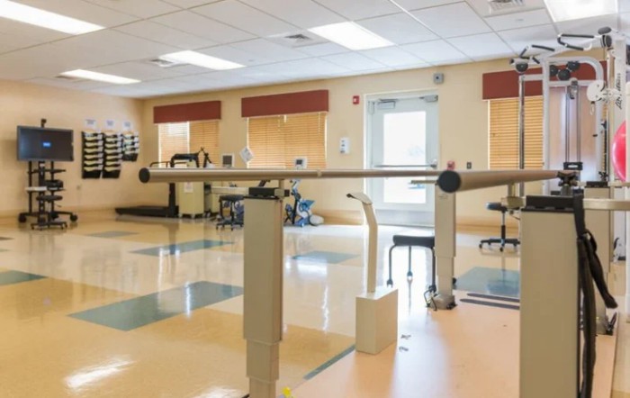 A well-equipped physical therapy room with parallel bars and exercise equipment.