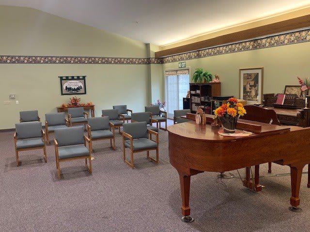 A cozy room with a grand piano and seating arrangements, adorned with a flower centerpiece.
