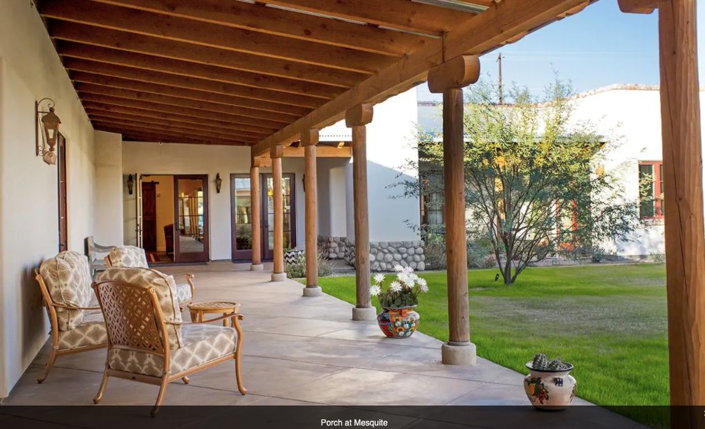 A tranquil patio area with wooden beams, outdoor seating, and a view of the garden.