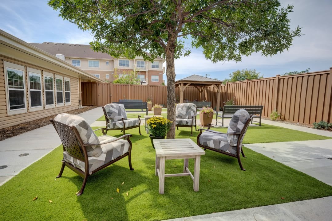 A cozy outdoor patio area with several chairs and a table under a tree.