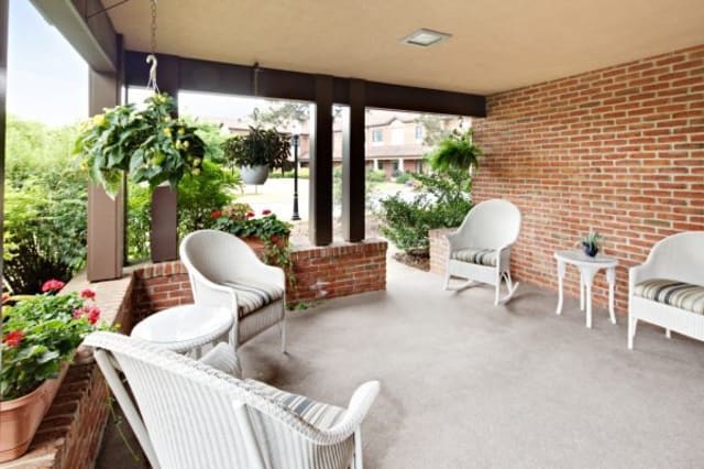 A cozy porch with wicker furniture and greenery offers a relaxing outdoor space.