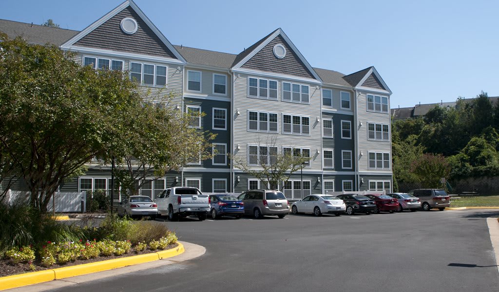Apartment building with a parking lot and several parked cars.
