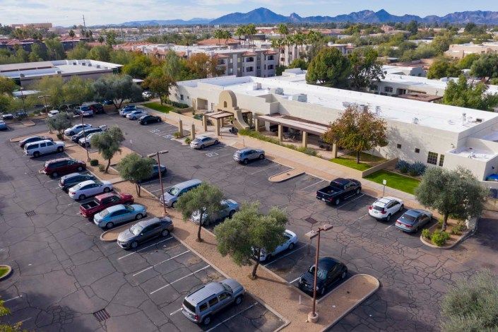 Aerial view of a parking lot adjacent to buildings with mountains in the background.