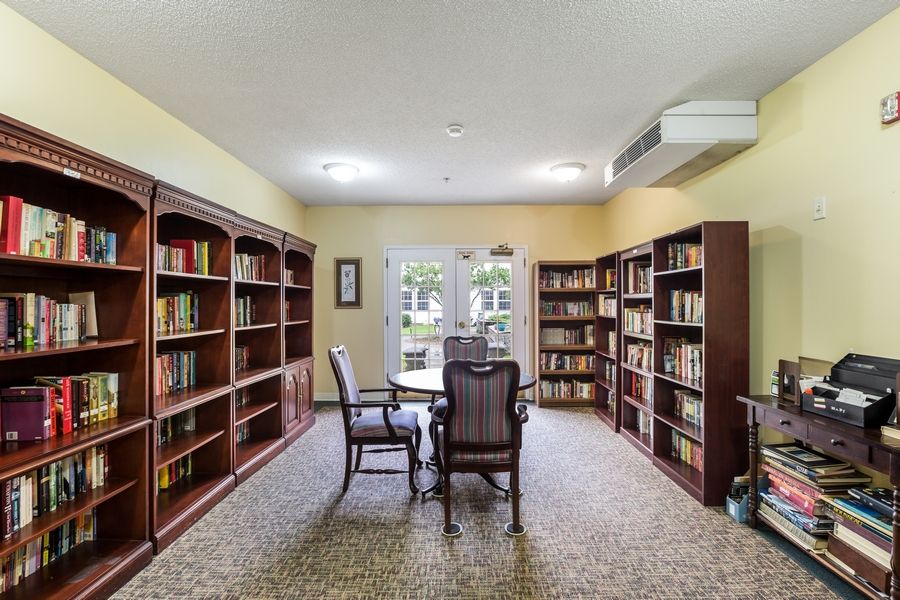 A cozy library room with bookshelves, a table, and chairs.