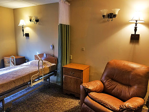 A cozy hospital patient room featuring a bed and an armchair, designed for comfort.