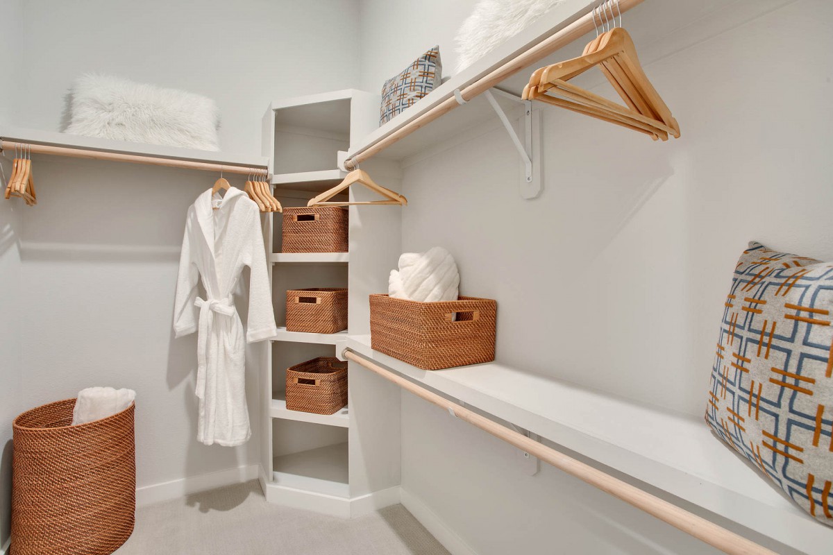 A neatly organized walk-in closet featuring shelves, hangers, and storage baskets.