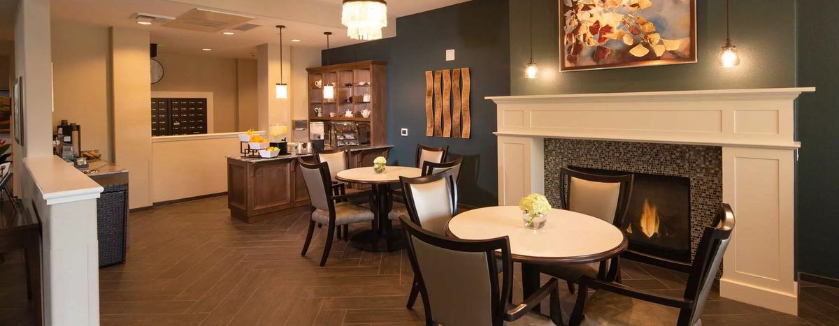 A cozy dining area with elegant interior design, featuring round tables, cushioned chairs, and a modern fireplace.