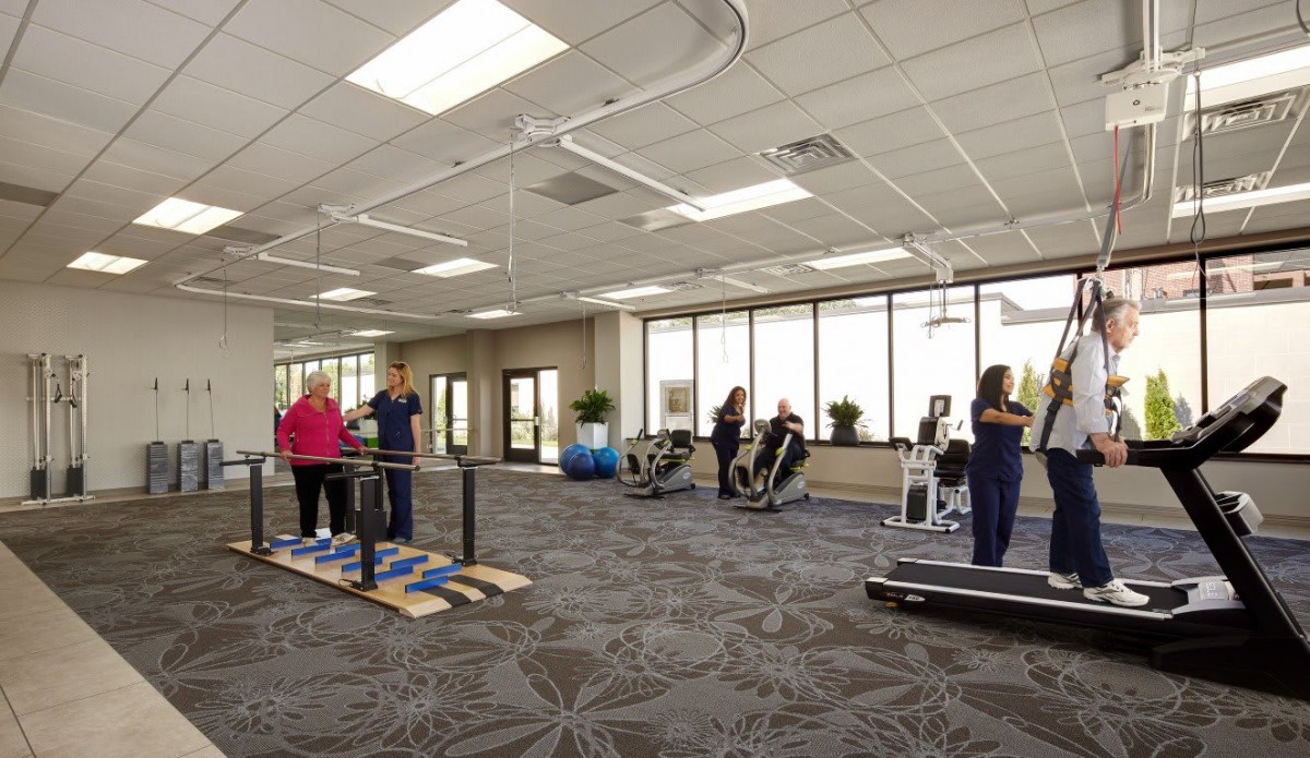 A rehabilitation center with exercise equipment and people engaged in physical therapy.