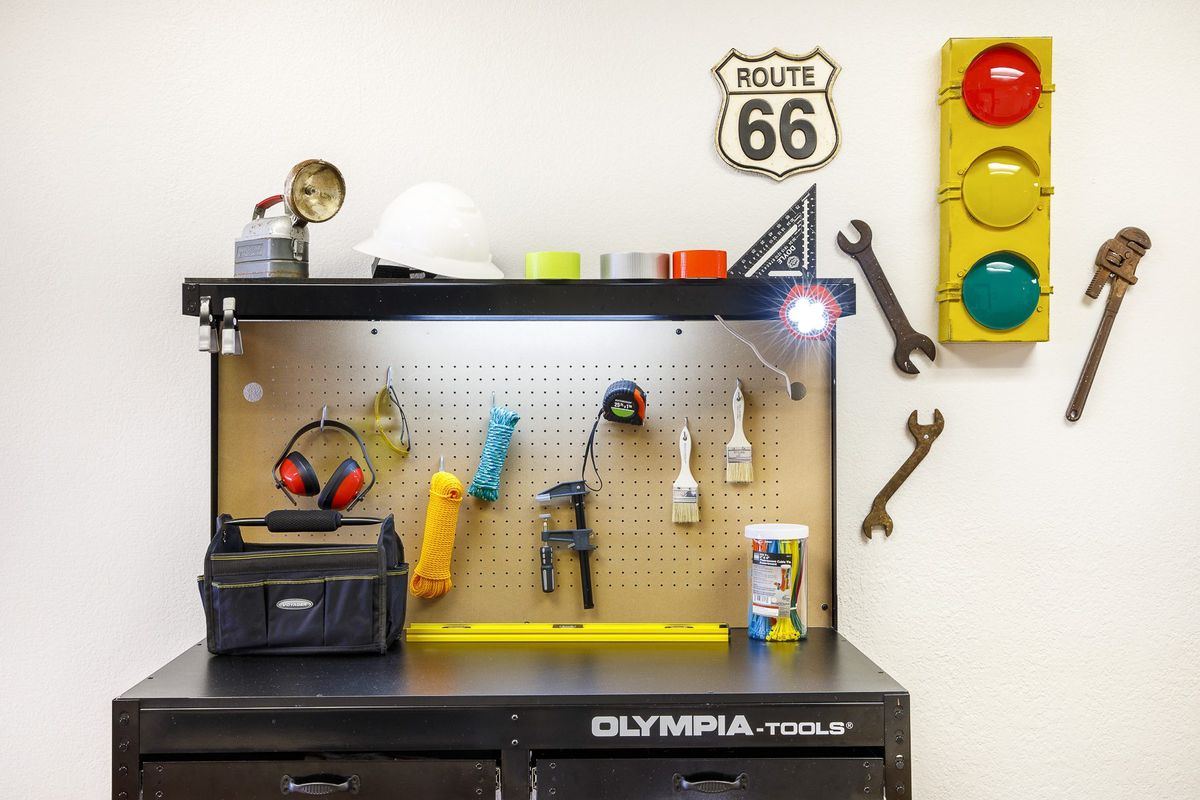 A well-organized workbench featuring various tools and decorations, including a Route 66 sign and a traffic light.