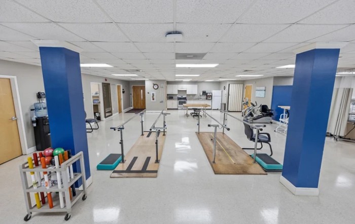 A well-equipped physical therapy room featuring parallel bars and various exercise equipment in a healthcare facility.