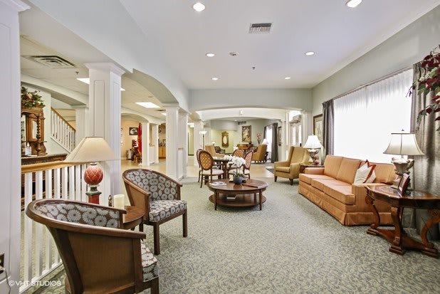 A spacious and elegantly furnished living room with sofas, chairs, and decorative items.