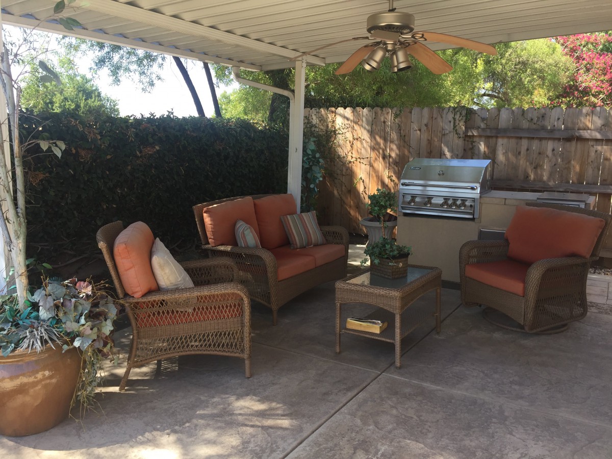 A cozy outdoor patio setup with comfortable seating and a grill.