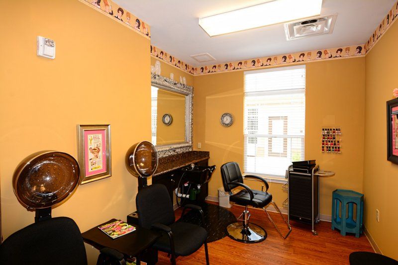 A cozy hair salon interior featuring chairs, mirrors, and a hair dryer, with warm decor and natural light from the window.