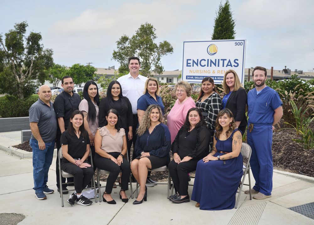 A professional team poses for a group photo in front of a sign that reads 'Encinitas'.