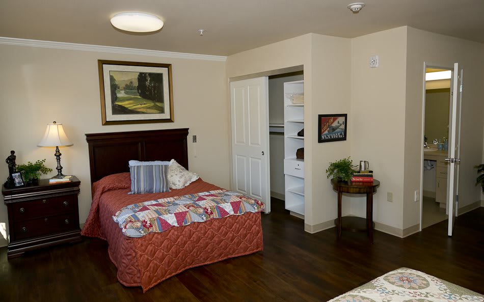 A cozy bedroom with a single bed, artwork on the wall, and an open closet.