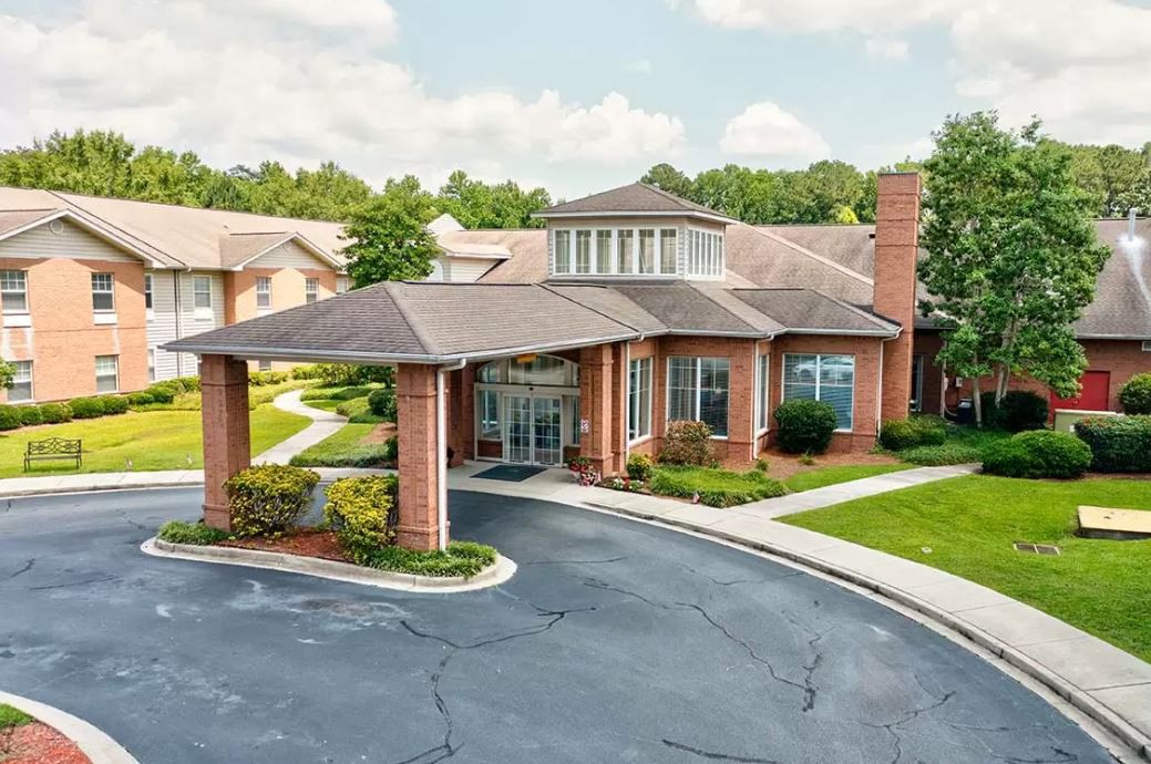 A suburban residential building with a driveway and landscaped surroundings.