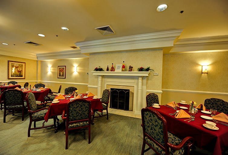 A cozy dining room with elegantly set tables and a fireplace.