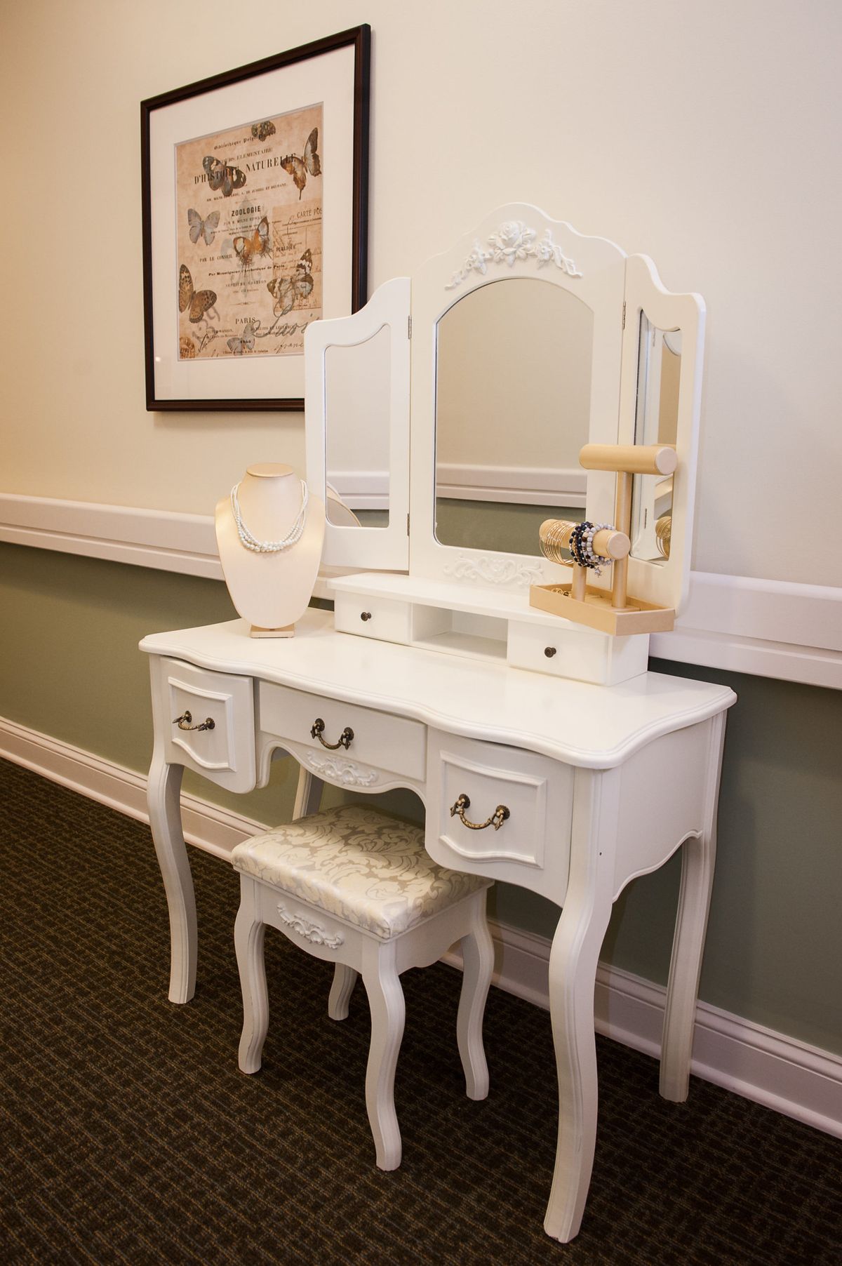 A vintage-style white vanity with a mirror and matching stool.