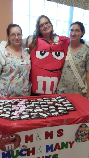 A fun gathering with someone dressed as an M&M, surrounded by friends and a table full of candy.