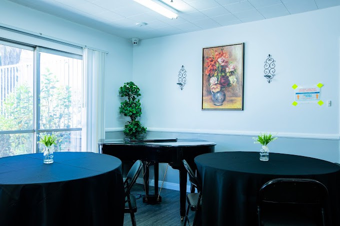An elegantly decorated dining area with black tablecloths, a piano, and wall art.