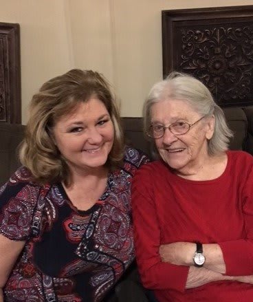 Two women sitting together, smiling for the camera.