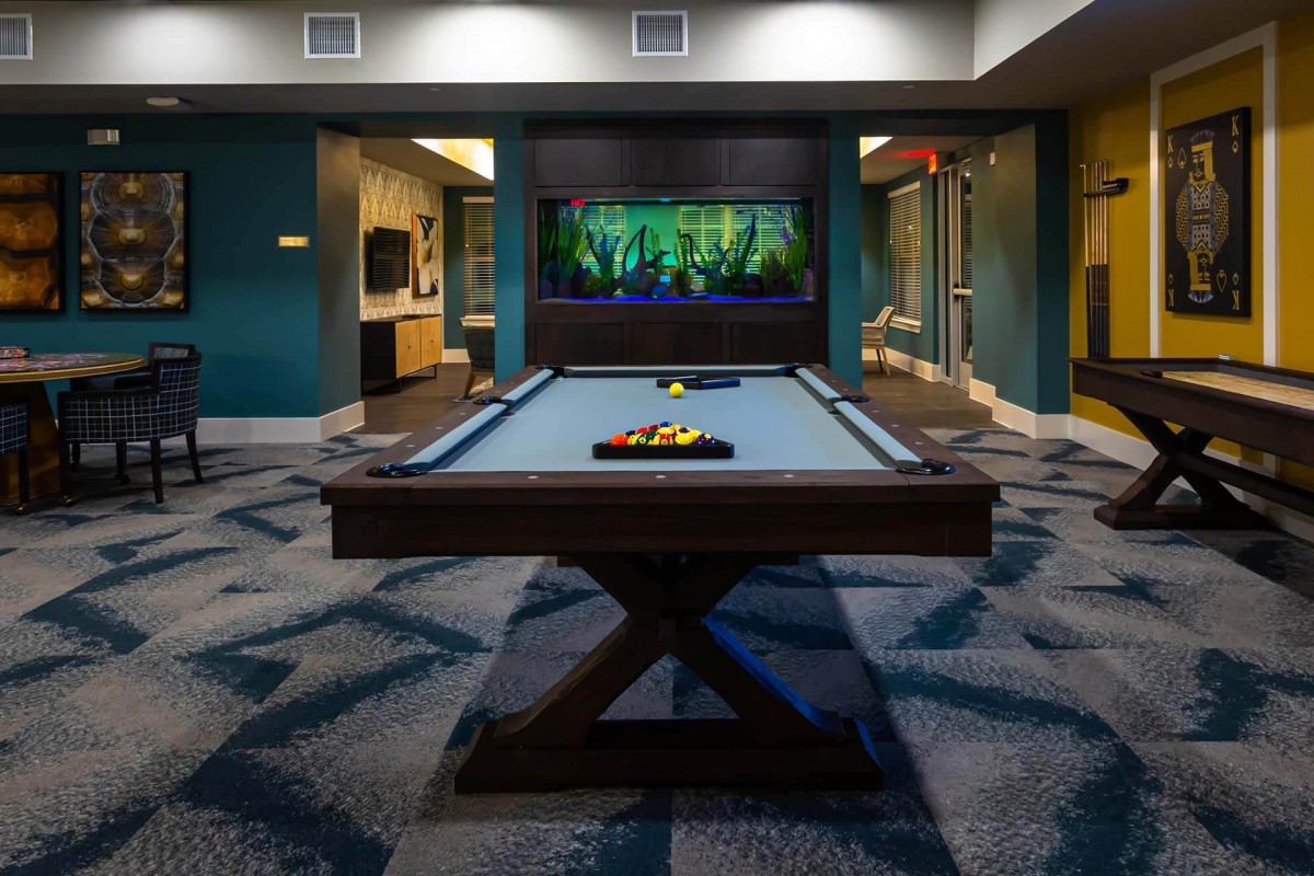 A modern game room featuring a pool table and a large aquarium.