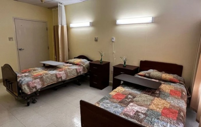 A hospital room with two beds and bedside tables.
