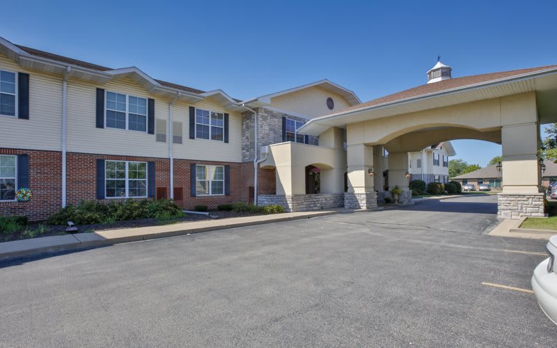 An exterior view of a residential building, possibly an assisted living facility, featuring a covered entrance.