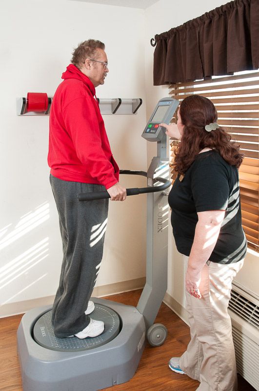 A person using a fitness machine with assistance from a trainer.