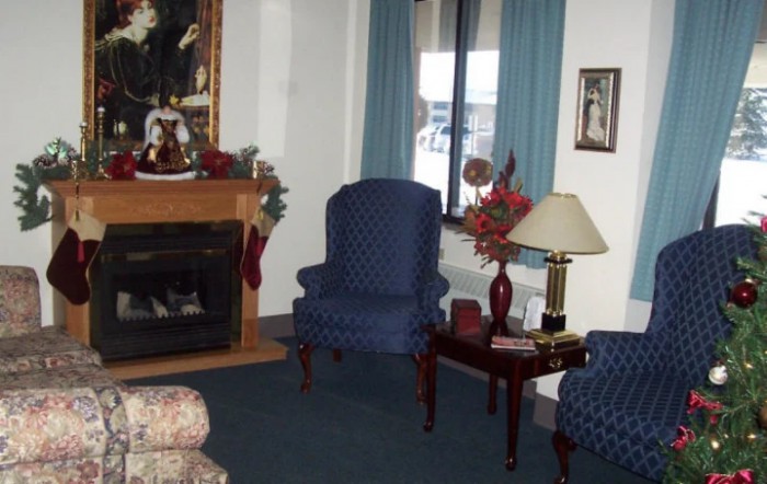 A cozy living room with a fireplace, armchairs, and decorative elements.
