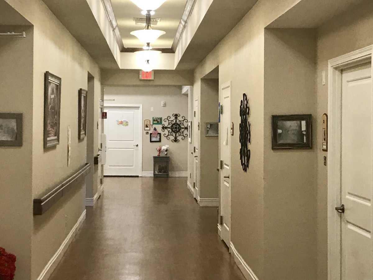 A well-lit hallway with framed decor and multiple doors along its walls.