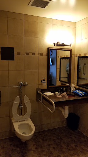 A well-equipped bathroom featuring a toilet, sink, and mirrors, designed for accessibility.