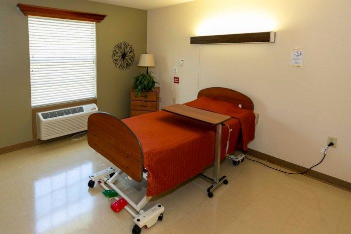 A clean and well-organized hospital room with a single bed and medical equipment.