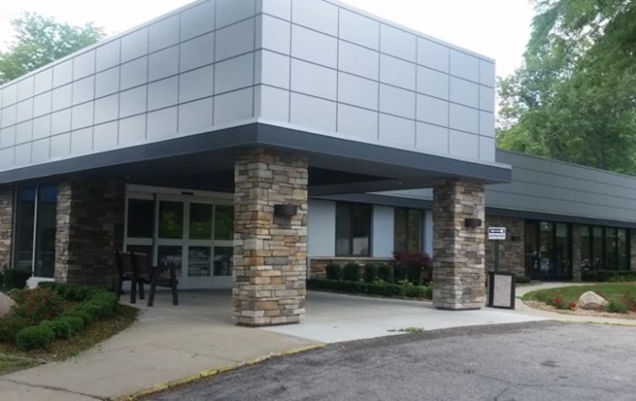 A modern building entrance featuring stone columns and a paved pathway.
